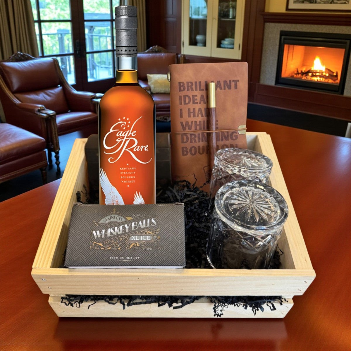Collector’s Eagle Rare 10 Year Bourbon Gift Crate with old-fashioned crystal-cut glasses, whiskey balls, and leather journal on table by fireplace – Rare Bourbon Shop lifestyle photo