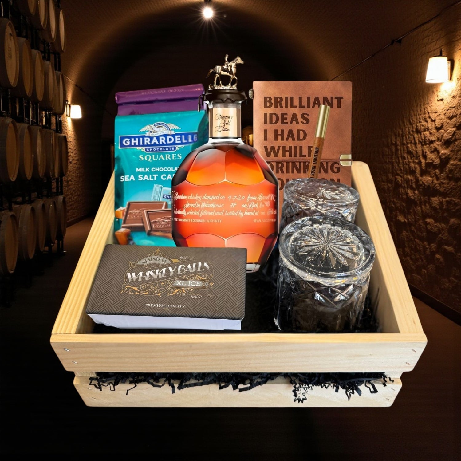 Blanton’s Gold Edition Single Barrel Bourbon Gift Crate with bottle, glasses, chocolate, and journal displayed in a wooden crate in a bourbon cellar – rare collector’s bourbon gift from Rare Bourbon Shop