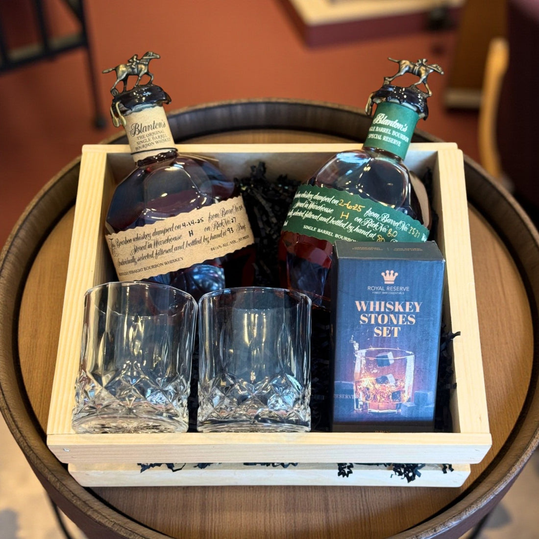 Collector’s Blanton’s Original and Special Reserve Bourbon Gift Crate with old-fashioned glasses and whiskey stones set on a barrel – Rare Bourbon Shop lifestyle photo