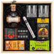 Blanton's Straight From The Barrel Single Barrel Bourbon 700ml gift crate with bronze horse stopper and gold wax cap, crystal-cut old fashioned glasses, Royal Reserve whiskey stones set with tray, Montecristo Platinum cigar tube, Black Rifle Coffee Tactisquatch blend, Chocolove Almonds & Sea Salt dark chocolate bar, and Wonderful Pistachios in black crinkle paper on white background