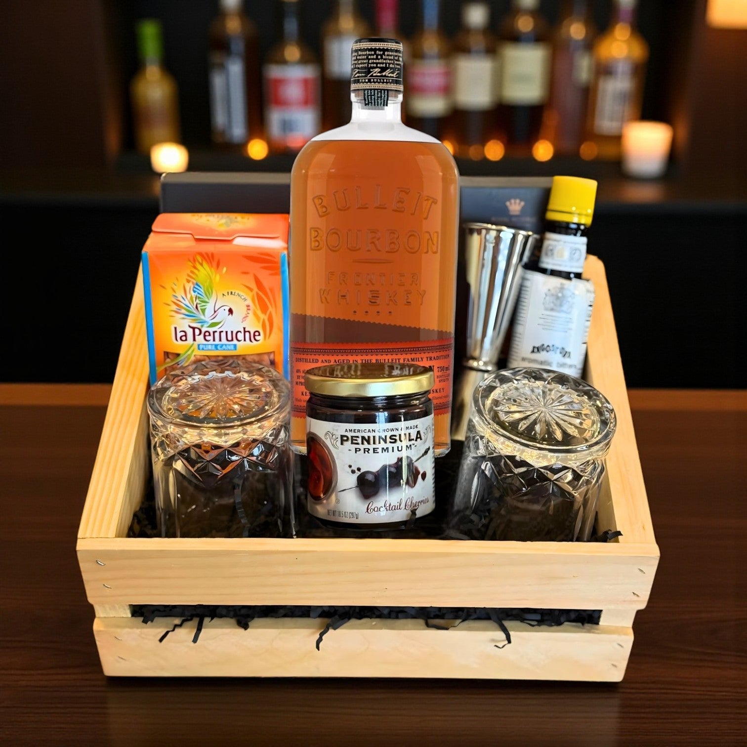 Collector’s Bulleit Bourbon Old Fashioned Gift Crate with whiskey, bar tools, cocktail cherries, bitters, and glasses on bar – Rare Bourbon Shop lifestyle photo