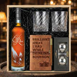 Eagle Rare 10 Year Kentucky Straight Bourbon Whiskey gift crate with orange label and white eagle illustration, crystal-cut old fashioned glasses with diagonal twisted swirl pattern, tan leather bourbon journal and pen set, and Stanley's XXL stainless steel whiskey balls on rustic wood surface with warm ambient lighting