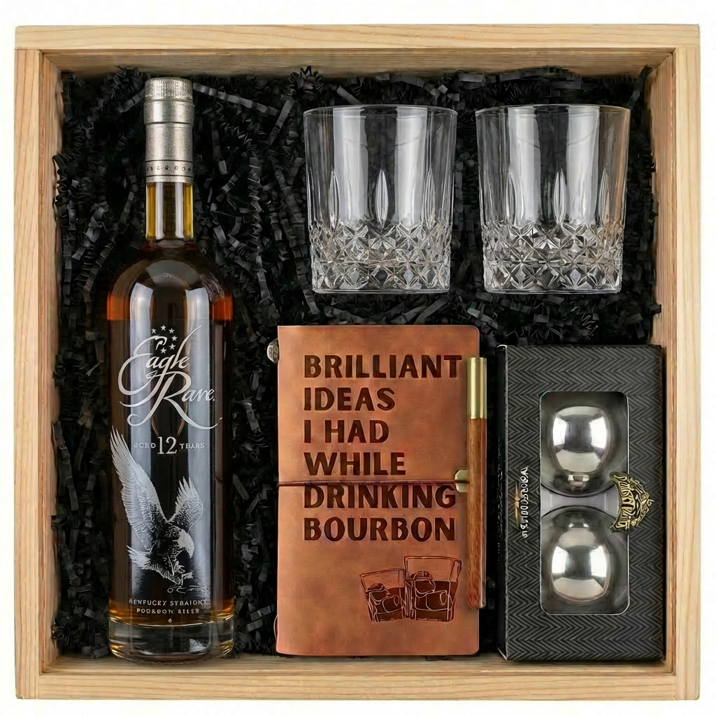 Eagle Rare 12 Year Old Kentucky Straight Bourbon Whiskey gift crate with crystal whiskey glasses, leather bourbon journal with brass pen, and stainless steel whiskey balls on black crinkle paper fill