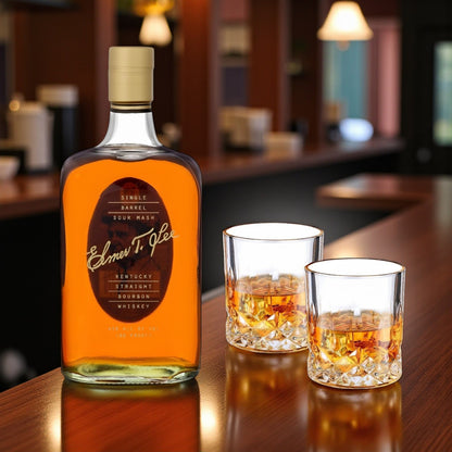 Elmer T. Lee Single Barrel Bourbon and two engraved glasses displayed on a wooden bar in warm lighting – Top Bourbon luxury presentation