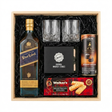 Johnnie Walker Blue Label Scotch Gift Crate featuring a 750ml bottle, two crystal cut whiskey glasses, Original Whiskey Stones set, Walker's Shortbread Fingers, and Turin Johnnie Walker Bittersweet Chocolates tube, arranged in a light wooden gift box with black crinkle paper