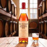 Collector’s Pappy Van Winkle Family Reserve 13 Year Straight Rye Whiskey bottle on rustic wooden table beside glass of rye with bourbon barrels in background – Rare Bourbon Shop lifestyle photo