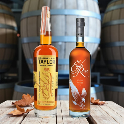 Collector’s Eagle Rare and Colonel E.H. Taylor Small Batch Bourbon bottles on wooden table with bourbon barrels and autumn leaves – Rare Bourbon Shop lifestyle photo