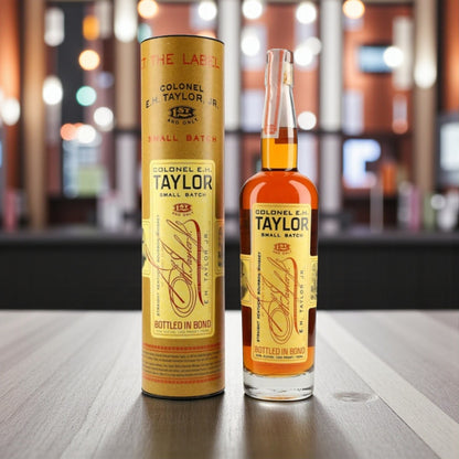 Collector’s Colonel E.H. Taylor Small Batch Bottled in Bond Bourbon bottle and tube on polished bar with lighting – Rare Bourbon Shop lifestyle photo