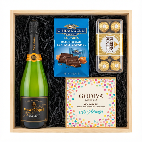 Veuve Clicquot Extra Brut Extra Old Champagne gift crate with black label and orange foil, Ghirardelli Dark Chocolate Sea Salt Caramel squares, Godiva Let's Celebrate chocolate box, and Ferrero Rocher chocolates in black crinkle paper on white background