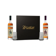Black Willett gift box flanked by Willett Family Estate rye and bourbon 750ml bottles and two etched Willett glasses.